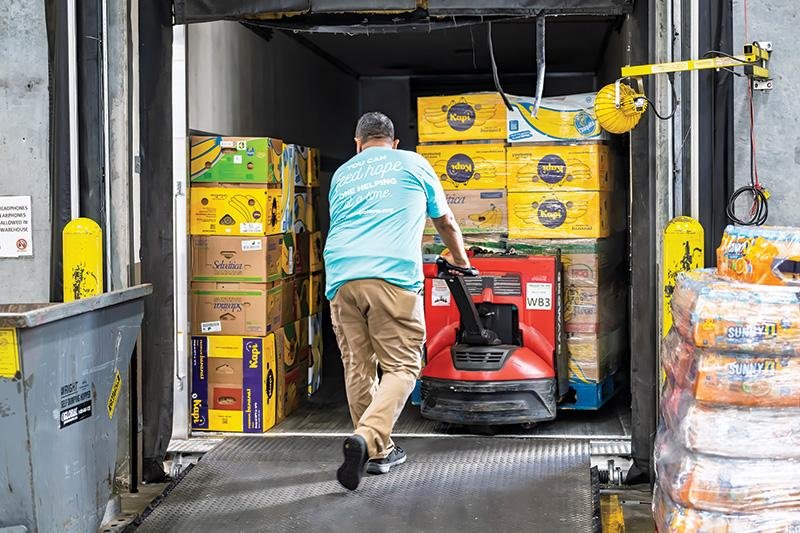 Food donations being loaded into cold-chain vehicle at nonprofit warehouse.